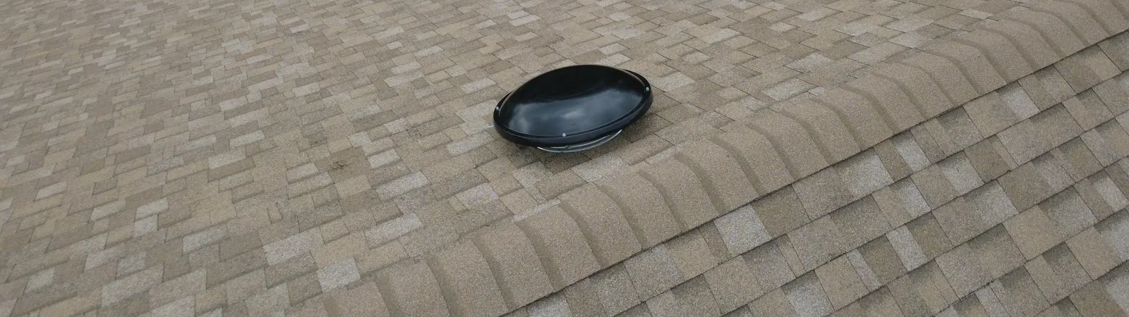 Installed tan shingles, ridge caps and roof vent