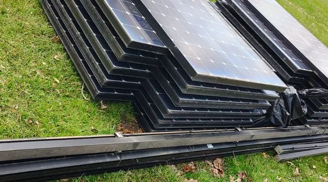 Removed solar panels at ground level with long rail sections beside them in Pine Hill, New Jersey